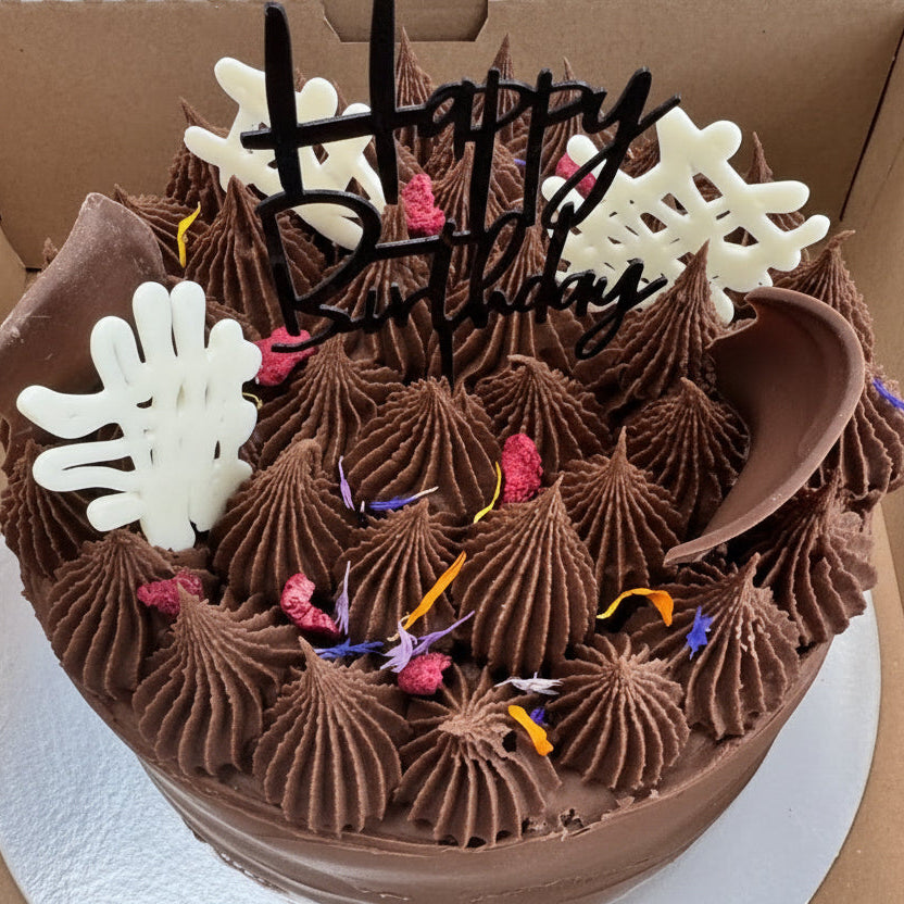 Chocolate birthday cake with 'Happy Birthday' decoration in a box